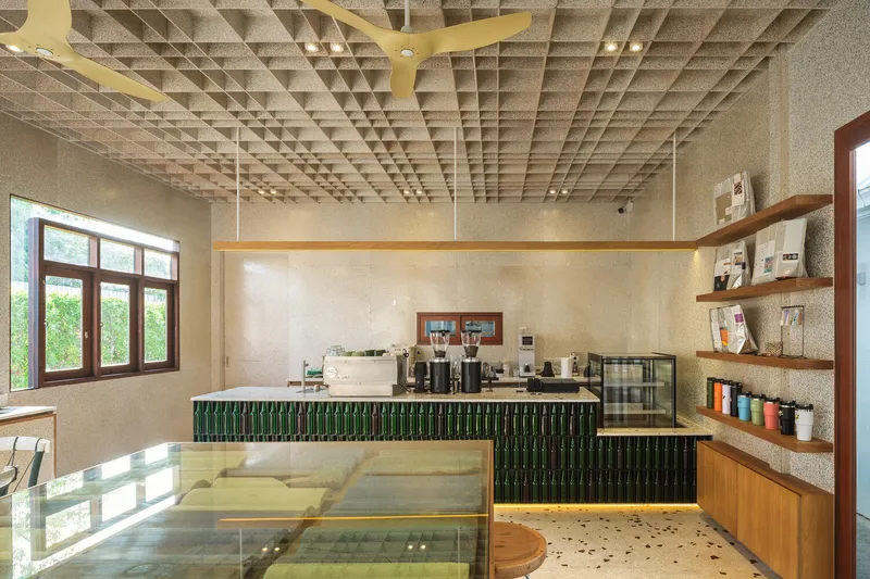 Counter interior: green bottle bar front, terrazzo countertop with glass shards, waffle ceiling, timber shelves