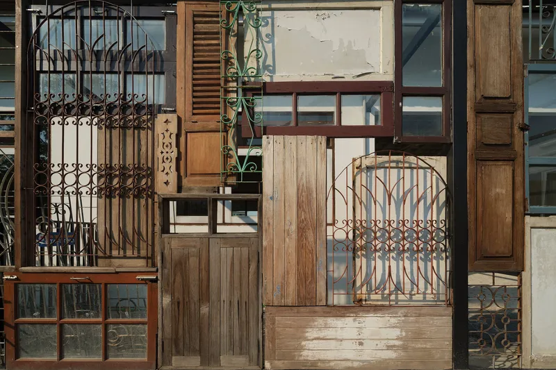 Facade close-up: the full collage of salvaged ironwork, timber shutters, louvres, and glass panels