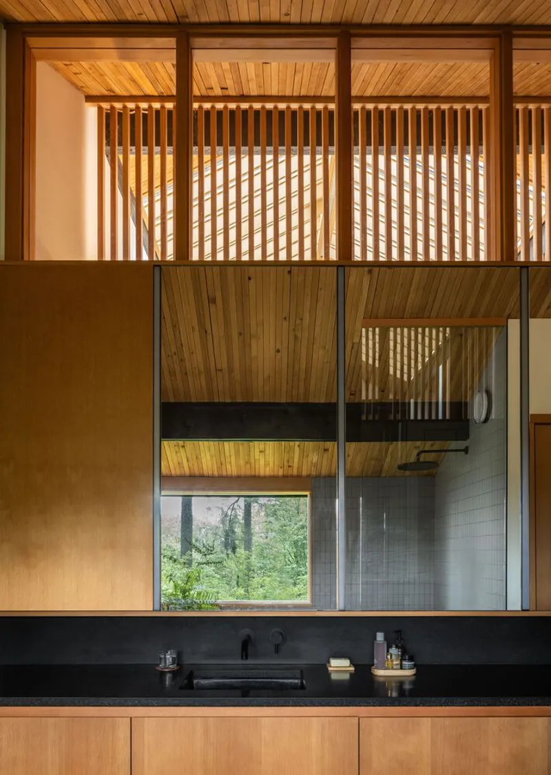 Kitchen counter with black stone backsplash below timber ceiling and vertical wood screen filtering afternoon light