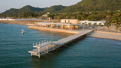 This architectural image showcases a modern pier extending into the sea, connected to a coastal rest