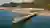 This architectural image showcases a modern pier and beachfront restaurant complex. The pier extends