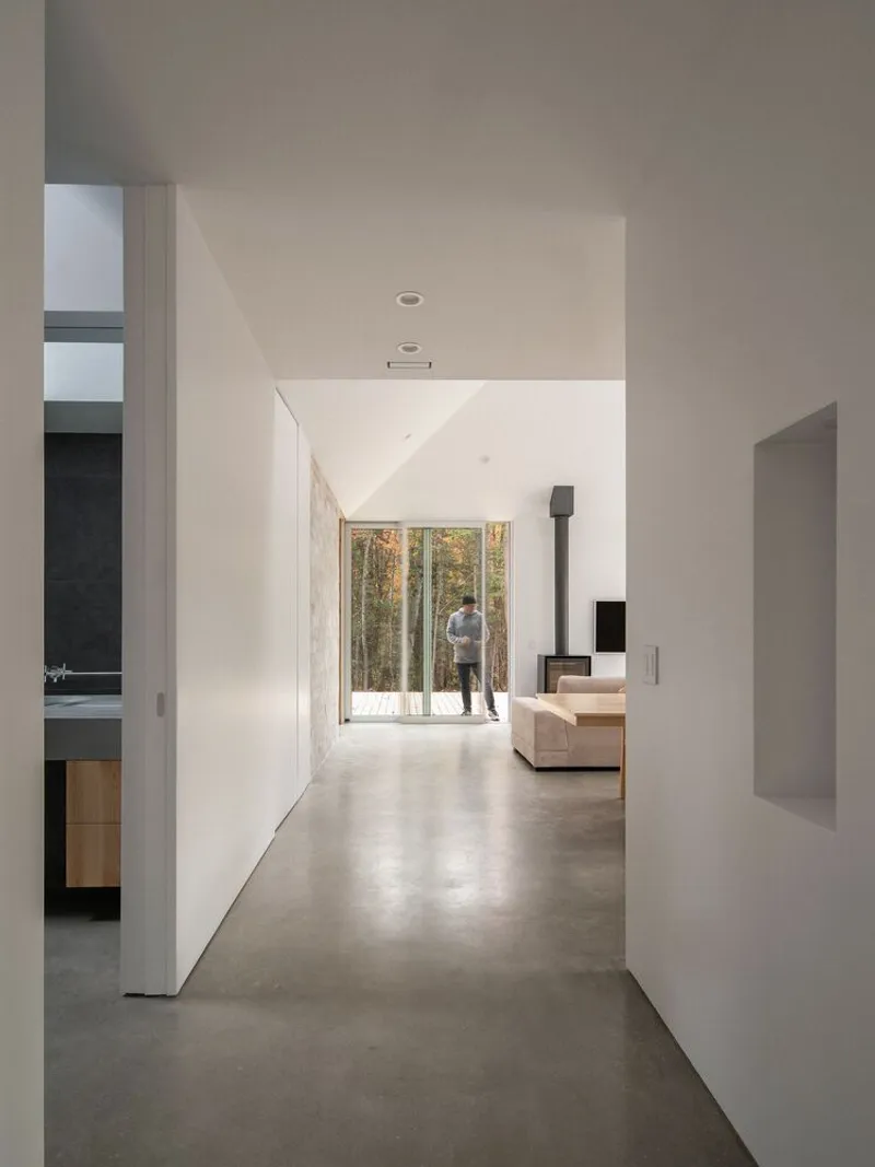 Entry corridor: white walls, polished concrete floor, living room with wood stove visible at the far end