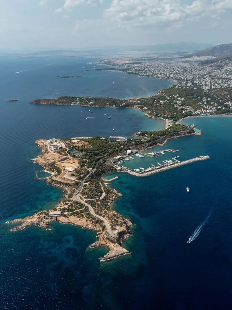 Aerial view of a rocky peninsula with marina, coastal roads and buildings surrounded by deep blue water