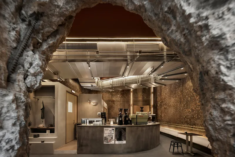 View through masonry arch toward illuminated service counter with exposed mechanical ductwork overhead