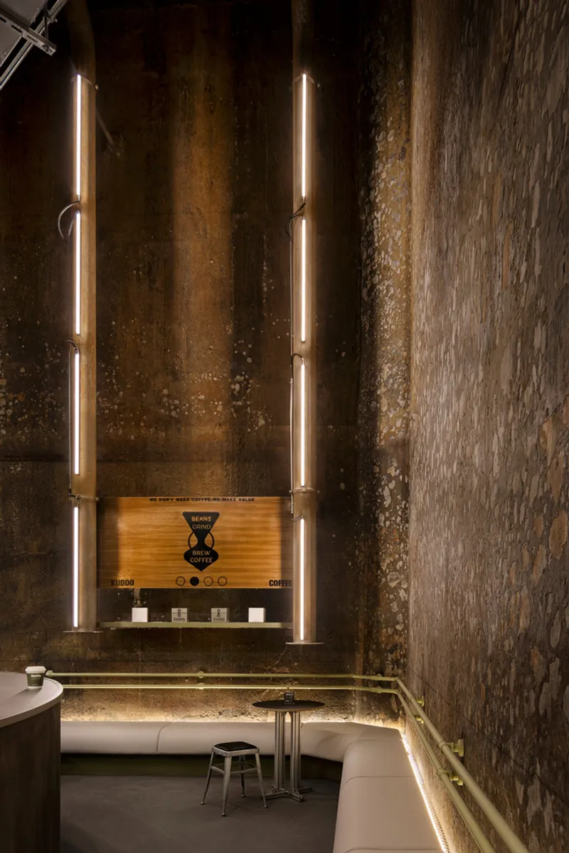 Seating alcove with vertical strip lighting flanking a menu board against textured concrete walls