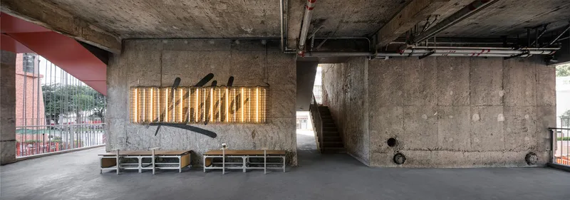 Wide view of the concrete undercroft showing the illuminated timber screen and exposed structural columns