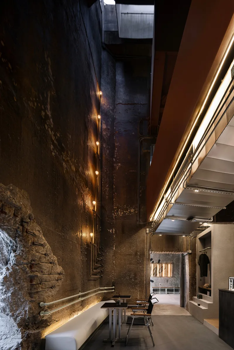 Upward view of the double-height interior space revealing weathered concrete walls with embedded lighting fixtures