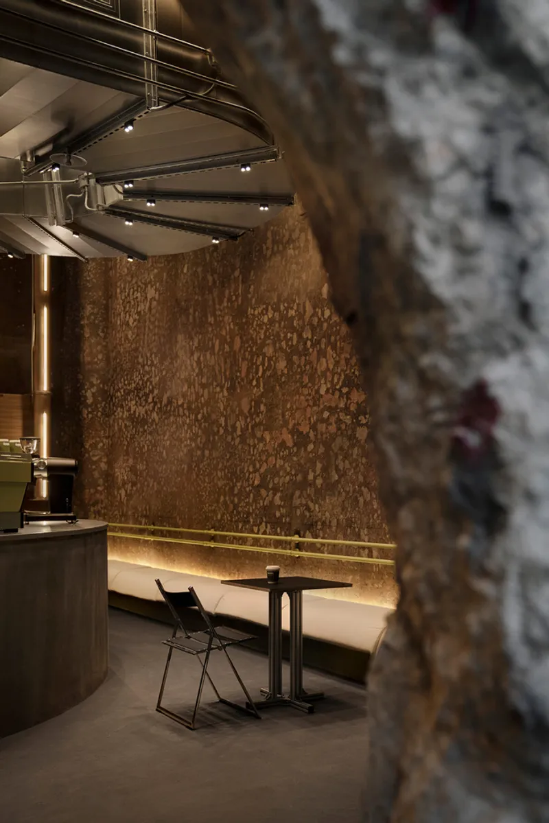 Detail of the weathered masonry wall with horizontal backlit bench seating and stainless steel staircase above