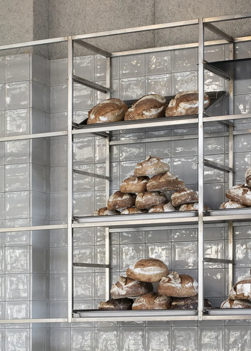 Detail: metal shelf with artisan sourdough bread loaves, grey tile wall behind