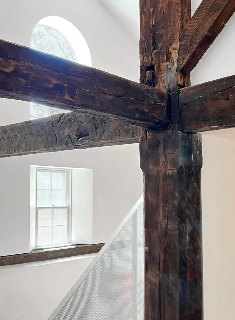 Exposed timber post and beam joint with steel connectors below a circular window