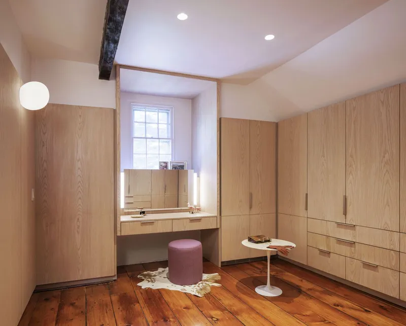 Dressing room with floor-to-ceiling oak veneer cabinetry and integrated vanity desk beneath vaulted ceiling