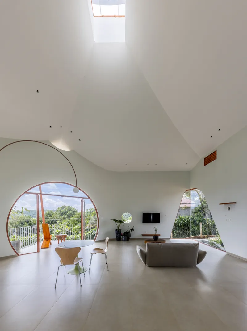 Living room with vaulted white ceiling, large arched windows and skylight overhead flooding the space with daylight