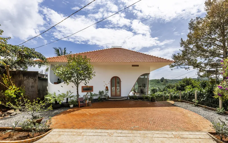Red clay tile roof over white walls with herringbone brick courtyard and surrounding foliage