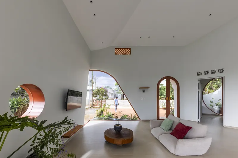 Living room with vaulted ceiling and asymmetric glazed opening framing a courtyard with person walking