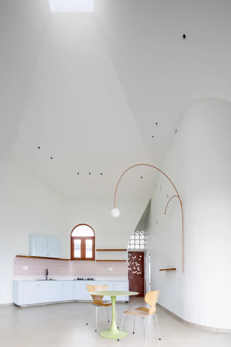 Open-plan kitchen and dining area with vaulted white ceiling and copper pendant lamp