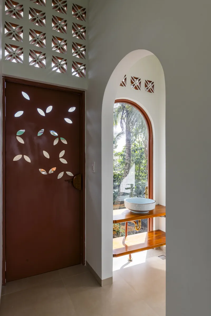 Arched bathroom niche with timber vanity and perforated door with leaf-shaped cutouts