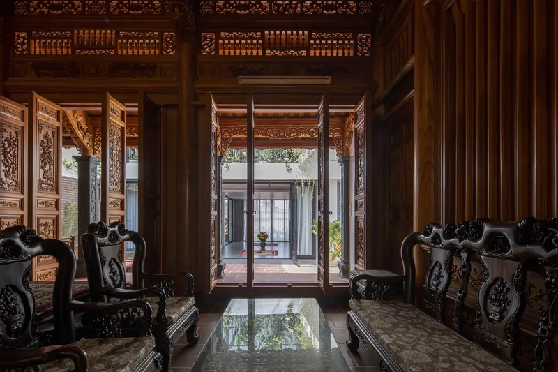 Inside the ancestral hall: ornate carved wood interior, traditional Vietnamese throne chairs and altar, view through doors to the courtyard