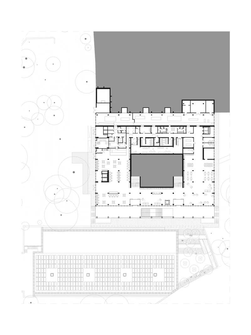 Floor plan drawing showing a U-shaped building wrapping around a central courtyard with trees