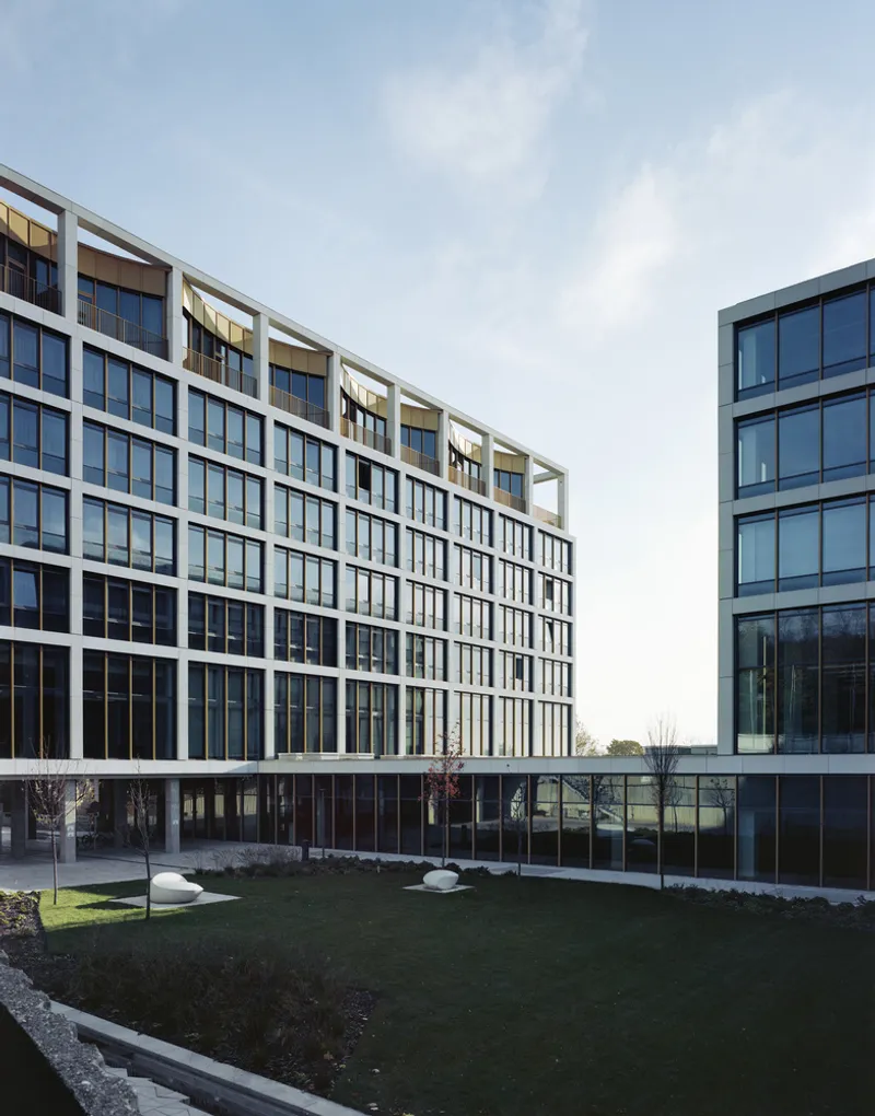 Courtyard view of the gridded glass facade with white concrete frame overlooking a planted lawn in winter