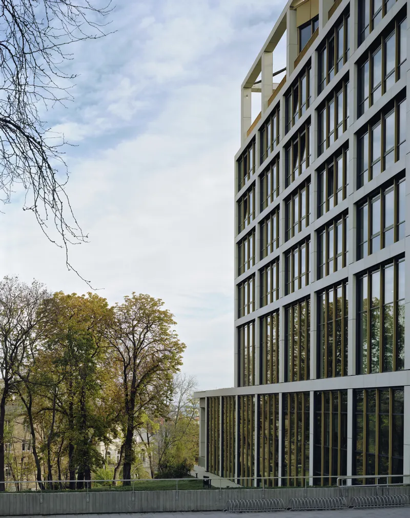Facade detail showing the white concrete frame and bronze-toned vertical fins against overcast sky