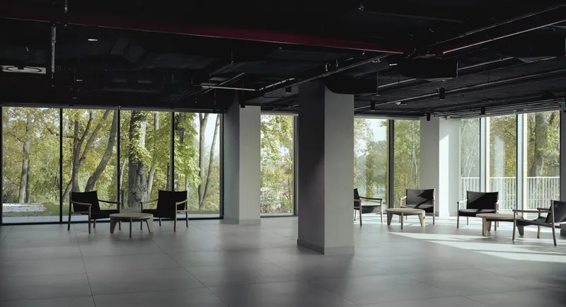 Open floor plan with white columns and seating groups facing full-height windows to wooded landscape