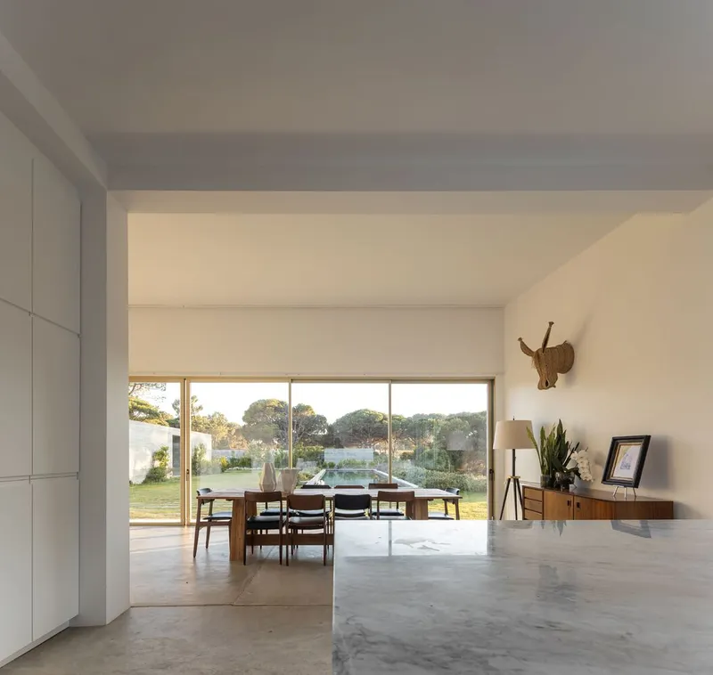 Dining area with polished concrete floor opening to garden through full-width sliding glass doors