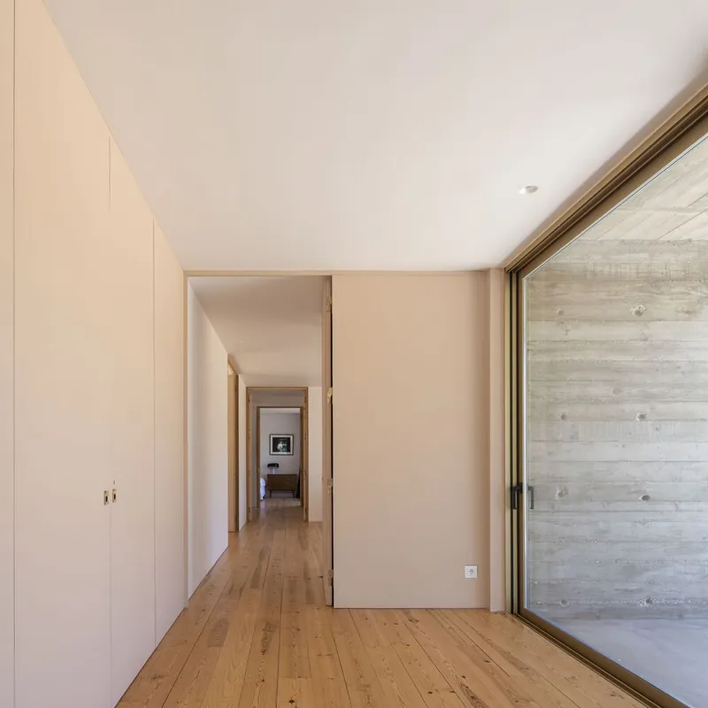 Corridor with pale wood flooring and built-in cabinetry leading to a distant room