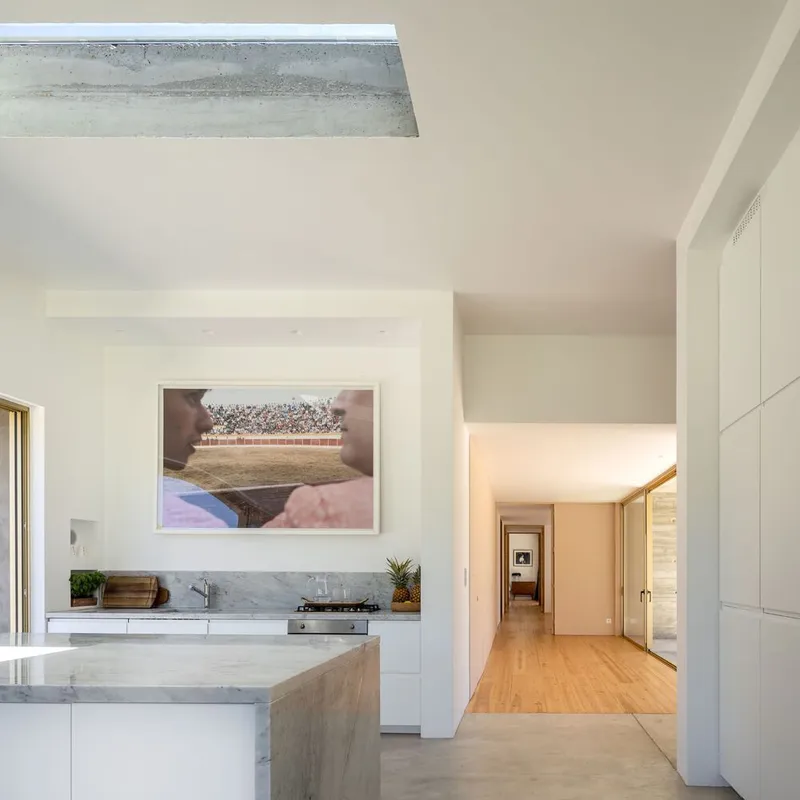 Kitchen with marble island and skylight above a hallway opening in soft daylight