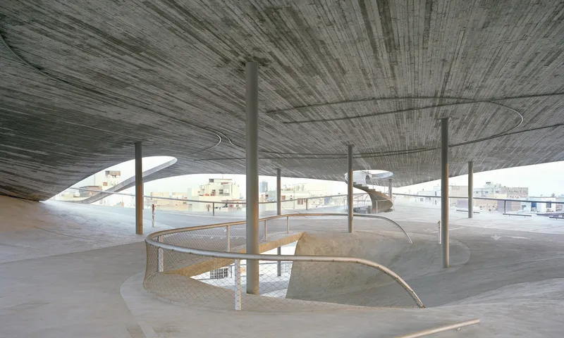 Interior view under the board-formed concrete roof slab with slender columns and curved stair openings