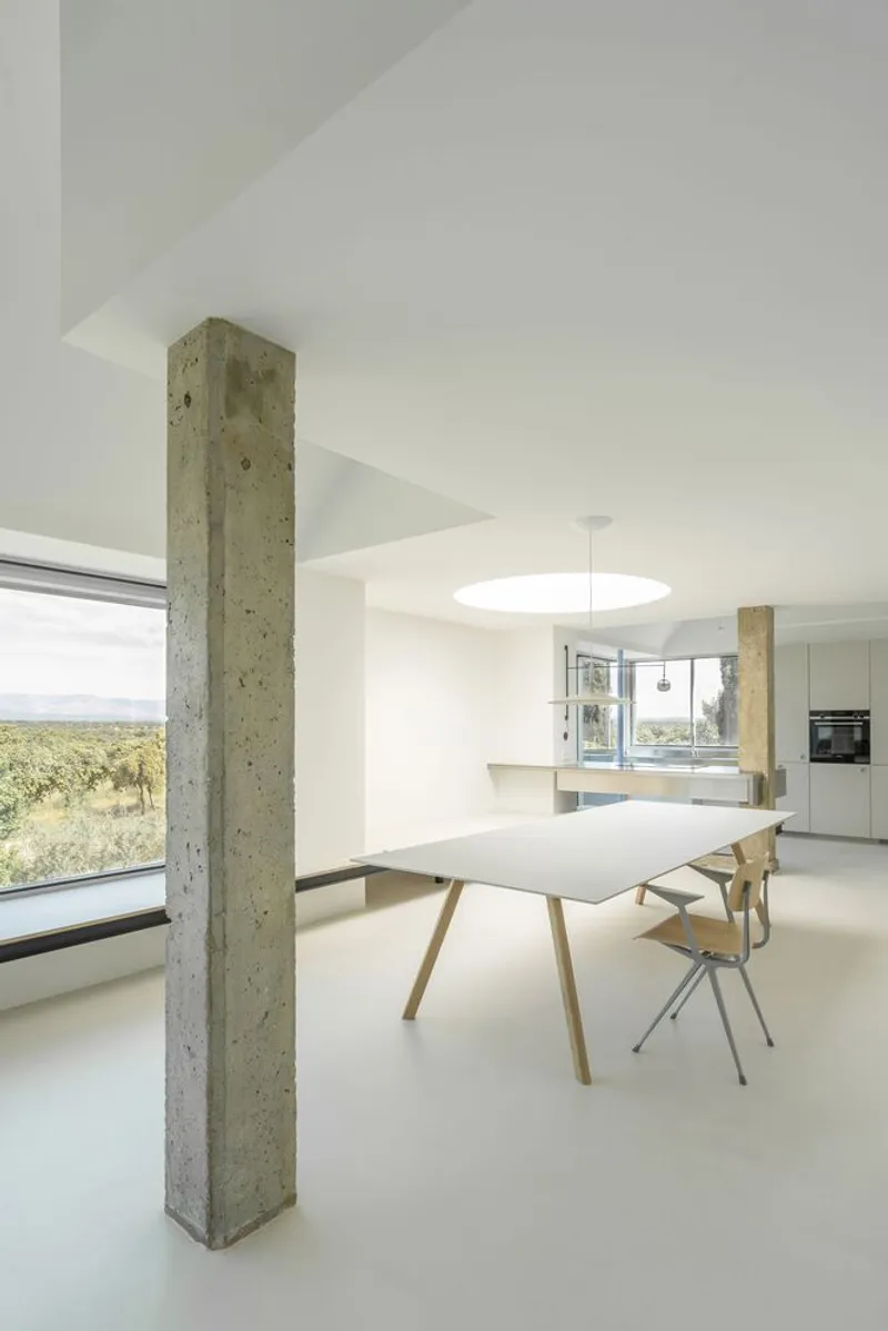 Dining area with freestanding concrete column and floor-to-ceiling glazing framing vineyard views
