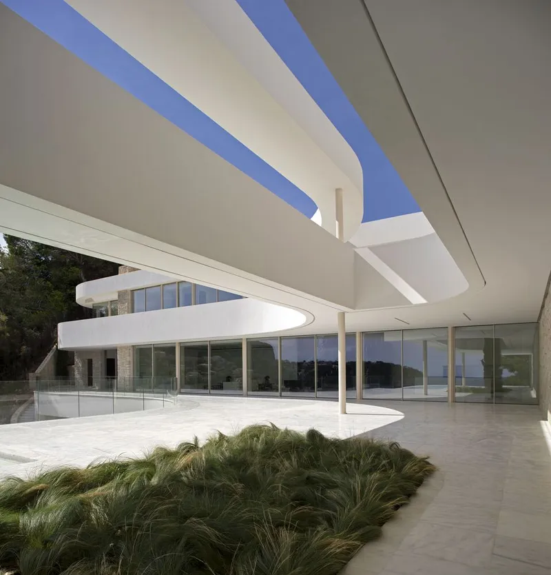 Covered terrace with white columns and curving soffit highlighting a planted bed of grasses