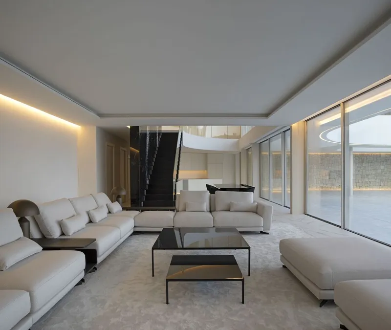 Living room with recessed ceiling, floor-to-ceiling glazing, and a black staircase descending to a lower level