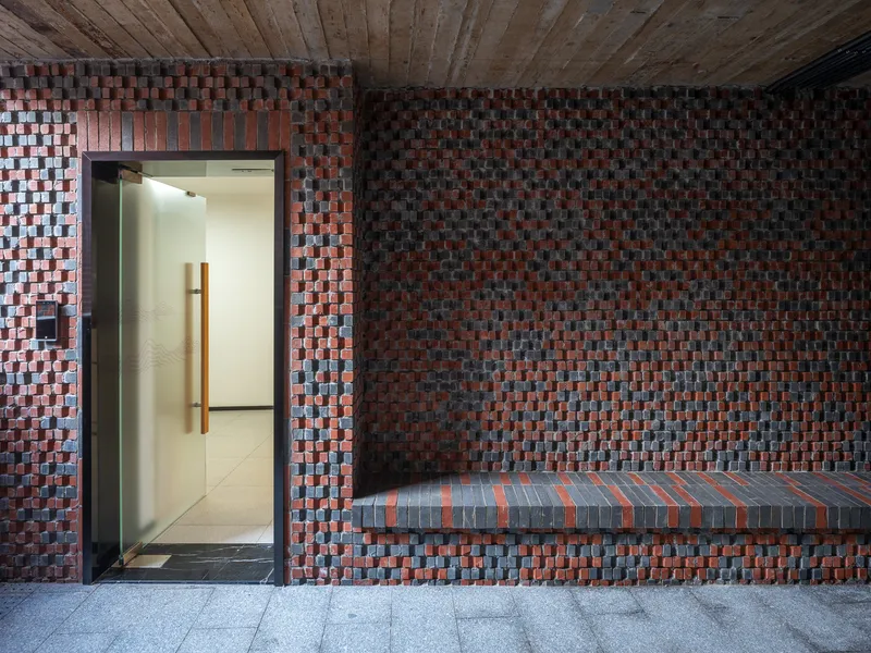 Interior corridor with multicolored brick wall, built-in bench and timber plank ceiling at dusk