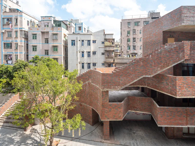 Arched brick passageways beneath curved ramps with a tree in the courtyard
