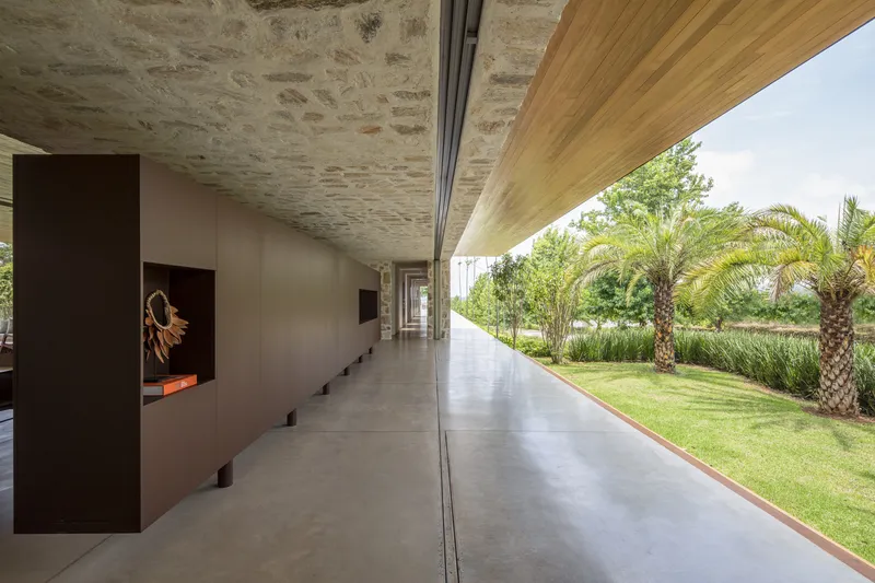 Gallery with stone vaulted ceiling and timber soffit opening to lawn with palm trees