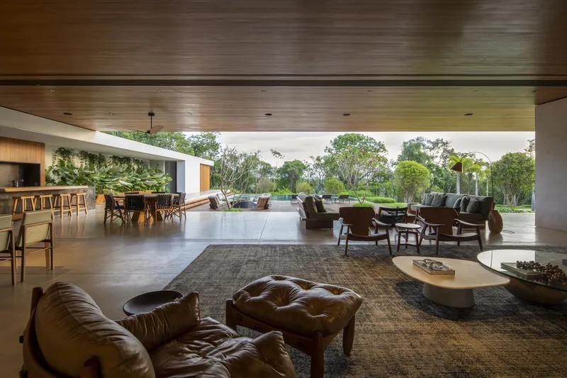 Open living area with timber ceiling overlooking a terrace and garden through floor-to-ceiling glass