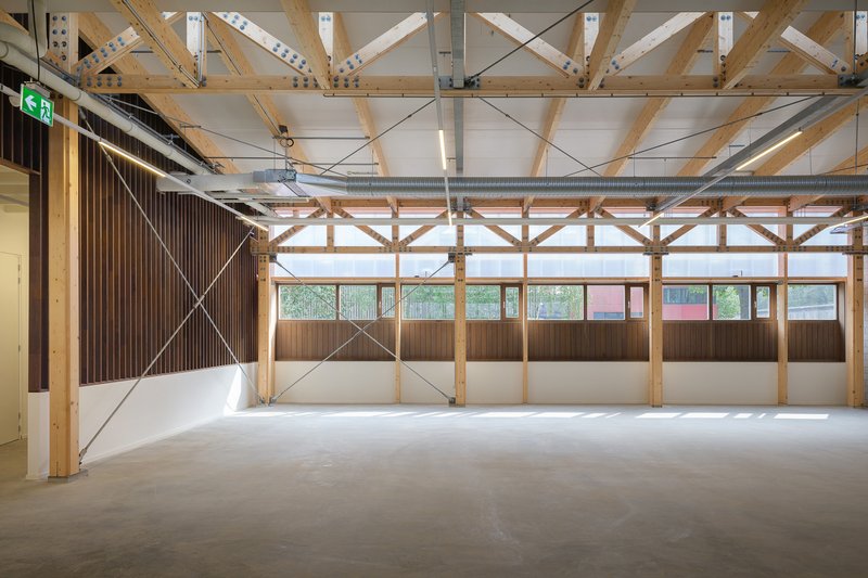 Interior space with exposed timber trusses and cross-bracing above a clerestory window wall