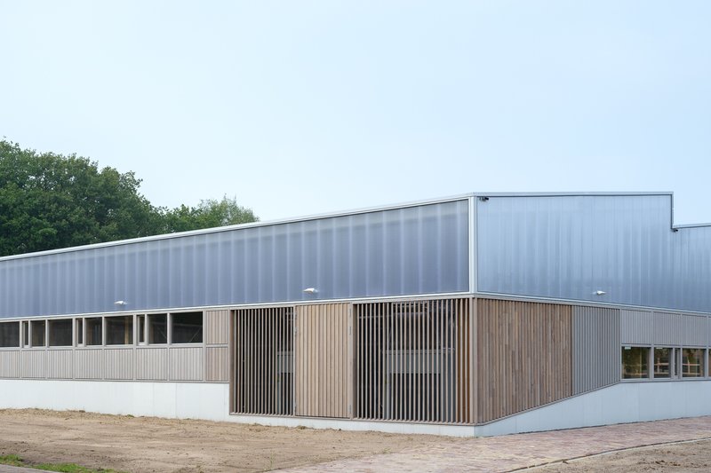 Corner entrance volume with vertical timber slat screen between metal and white panel facades