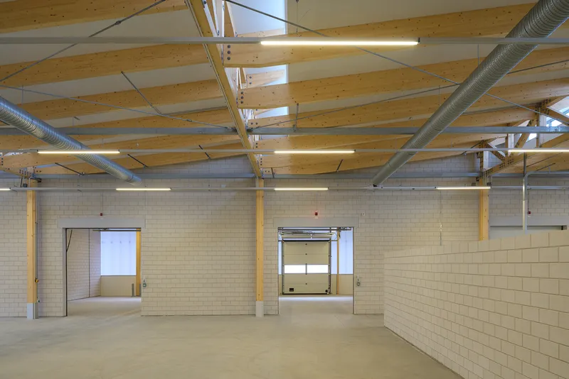 Industrial interior with exposed timber ceiling beams, metal ductwork, and cream-colored block walls