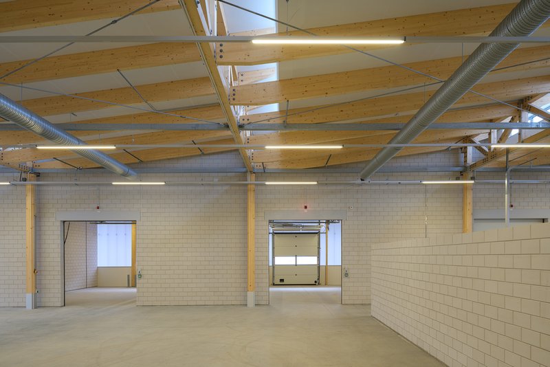 Industrial interior with exposed timber ceiling beams, metal ductwork, and cream-colored block walls