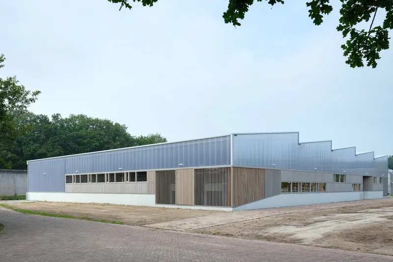 Corner view showing the stepped sawtooth roofline and timber-clad entry with clerestory windows