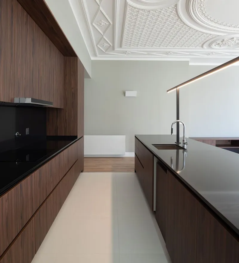 Galley kitchen with dark stone countertops under a plaster ceiling with diamond and lattice motifs