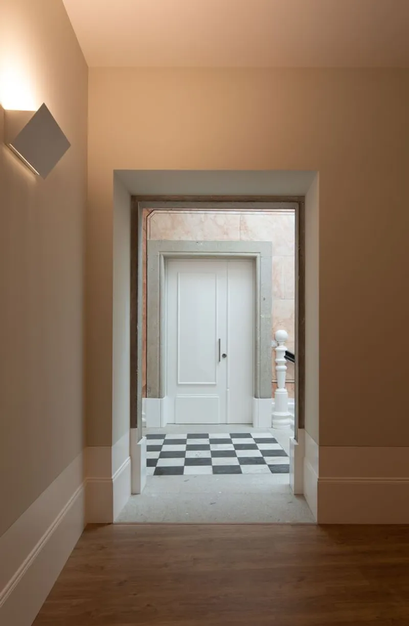 Enfilade through doorways revealing chequered marble flooring framed by warm painted walls