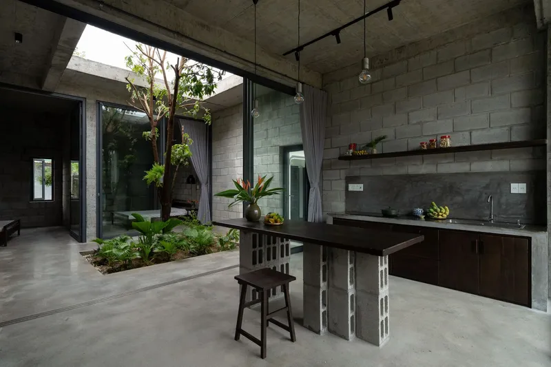 Open-air kitchen with concrete block walls and an internal courtyard garden with tropical plants