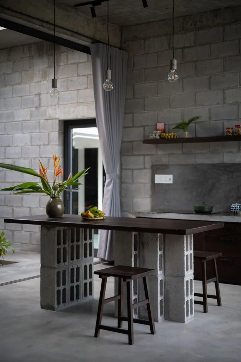 Kitchen island built from stacked concrete blocks with pendant lights hanging above dark timber stools