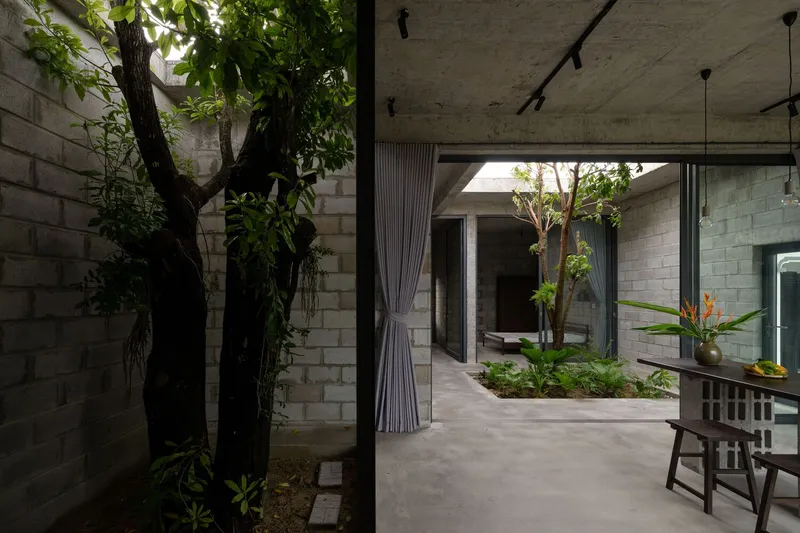 Interior corridor with exposed concrete ceiling and curtained opening framing the central courtyard with trees