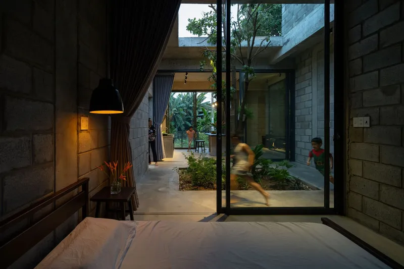 Bedroom view through glazed doors to interior courtyard with children moving through at dusk
