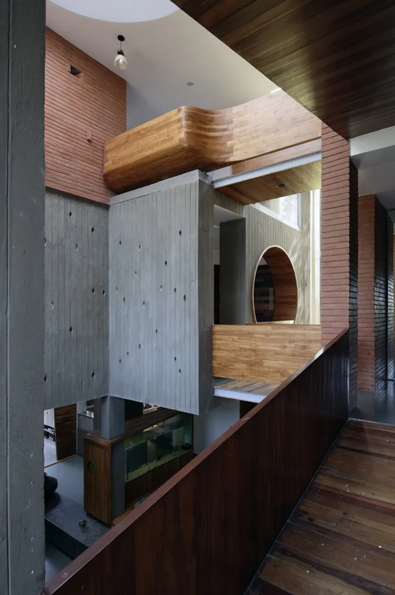 Upper level: timber balcony and bridge element, concrete column, arched timber opening below, brick wall beyond