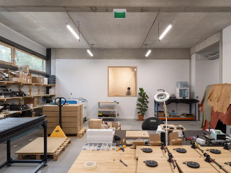 Fabrication room with timber framed window, person seated beyond, and tools scattered on benches