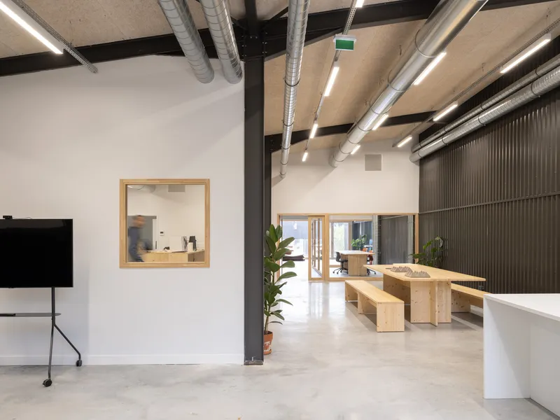 Interior corridor view through timber-framed openings with polished concrete floors and a potted plant in terracotta